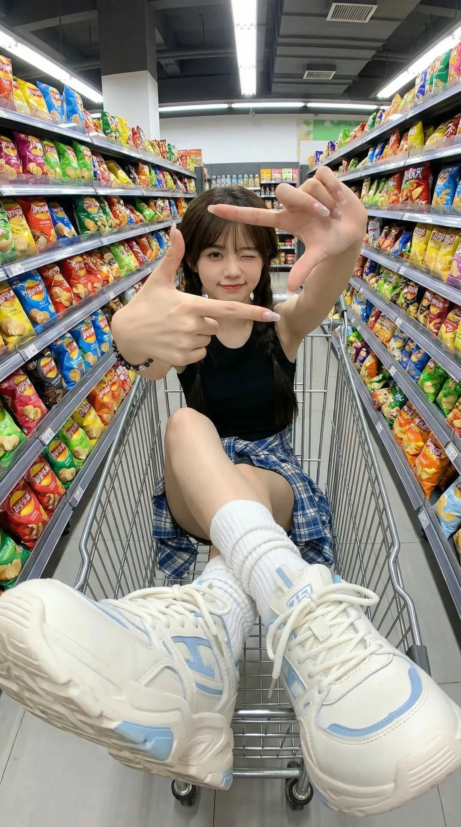 {
  "scene_description": "A playful, high-energy fisheye portrait of a stylish young woman sitting inside a metal shopping cart in a vibrant supermarket aisle.",
  "subject": {
    "type": "young woman",
    "age": "early 20s",
    "features": {
      "hair": "long dark brown hair tied in loose low pigtails",
      "expression": "playful wink, slight smile",
      "hands": "long manicured nails, making a finger-frame gesture around her eye"
    },
    "attire": "black tank top, blue and white plaid shirt tied around the waist, white scrunched socks",
    "footwear": "oversized chunky white sneakers with light blue accents and thick laces",
    "position": "sitting inside a wire shopping cart, legs extended toward the camera lens creating foreshortening"
  },
  "action": {
    "primary": "posing playfully inside a shopping cart",
    "secondary": "framing her winking eye with her fingers using an 'L' shape gesture",
    "effect": "dynamic distortion emphasizing the sneakers and hands due to the lens"
  },
  "environment": {
    "setting": "brightly lit grocery store snack aisle",
    "foreground_elements": [
      "silver metal wire of the shopping cart",
      "chunky sneaker sole in extreme close-up"
    ],
    "background_elements": [
      "shelves stocked with colorful snack bags (yellow, red, green packaging)",
      "overhead fluorescent lights",
      "tiled supermarket floor",
      "promotional signage on shelves"
    ]
  },
  "lighting": {
    "style": "high-key, flat commercial lighting",
    "key_light": {
      "type": "overhead fluorescent tubes",
      "color": "cool white/neutral",
      "illuminates": [
        "entire aisle evenly",
        "reflections on plastic snack packaging",
        "sheen on the metal cart"
      ]
    },
    "shadows": "minimal, soft shadows beneath the cart"
  },
  "style": {
    "medium": "digital photography",
    "aesthetic": "Gen Z social media trend, Y2K influence, street style",
    "quality": "high definition, vibrant colors",
    "details": "sharp focus throughout"
  },
  "scene_composition": {
    "subject_action": "Leaning back casually in the cart, engaging directly with the camera",
    "camera_behavior": "Extreme close-up, wide-angle distortion",
    "depth_layering": "Exaggerated foreground (shoes) -> Middle ground (subject) -> Curved background (shelves)"
  },
  "visual_description": {
    "core_subject": "A trendy young woman with a fun, carefree attitude.",
    "attire_physics": "The plaid shirt is bunched naturally around the waist; the shoe laces appear large and textured due to proximity.",
    "skin_rendering": "Smooth, bright complexion, soft makeup with emphasized blush."
  },
  "lighting_and_atmosphere": {
    "type": "Artificial Interior Lighting",
    "specifics": "Even, bright illumination typical of retail environments, creating vibrant color pop on the merchandise.",
    "color_grade": "Slightly overexposed highlights, saturated primaries (reds, yellows, blues)."
  },
  "attire_customization": {
    "current_clothing": "Black tank top, plaid shirt (blue/white/grey), denim shorts (hidden), white chunky sneakers.",
    "customizable_clothing": "Leave empty to maintain current style or replace with 'oversized hoodie' for a different vibe."
  },
  "brand_product_customization": {
    "current_brand_product": "Generic colorful potato chip bags and snack packaging in background.",
    "customizable_brand": "User can insert specific snack brand names for the shelves.",
    "customizable_product": "User can specify the type of sneaker (e.g., Jordan, Balenciaga).",
    "product_placement_area": "The shelves behind the subject or the yellow bag inside the cart."
  },
  "objects_and_props": {
    "main_objects": [
      "Metal shopping cart",
      "Chunky sneakers"
    ],
    "secondary_objects": [
      "Yellow snack bag inside the cart",
      "Silver scrunched bracelet"
    ]
  },
  "camera_and_lens": {
    "focal_length_feel": "8mm to 10mm Fisheye",
    "aperture_effect": "Deep depth of field (f/8 or f/11)",
    "camera_angle": "High angle / POV looking down into the cart",
    "lens_type": "Ultra-wide angle fisheye lens",
    "bokeh_style": "None (everything in focus)"
  }
}